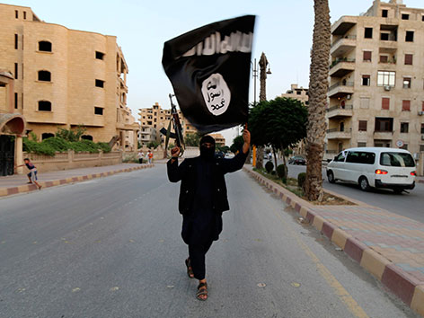 Ein ISIS-Kämpfer mit der Flagge des Islamischen Staates in der menschenleeren Stadt Kufa