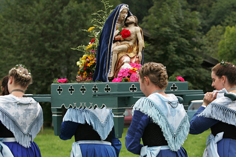 Junge Frauen tragen bei einer Prozession einen Marienstandbild