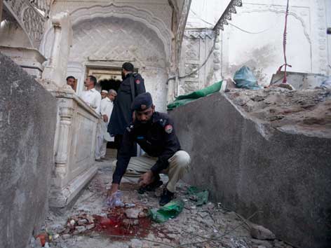 Ein Polizist untersucht Spuren einer Bombe in einem Heiligengrab in Pakistan.