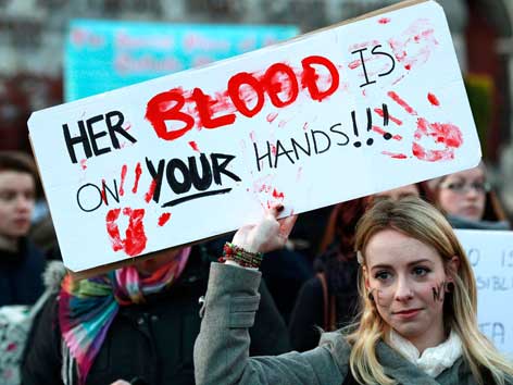 EIne Demonstrantin hält ein Schild mit der Aufschrift: Her blood is on your hands"