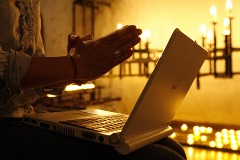 Betende Hände über Laptop in Kirche