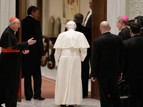 Papst Benedikt XVI., umringt von Priestern und Bischöfen, dreht der Kamera den Rücken
