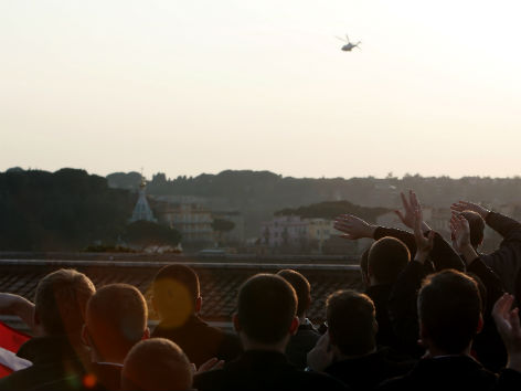 Priester beobachten den Abflug von Papst Benedikt im Hubschrauber