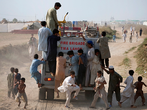 Junge Pakistanis klettern auf ein Feuerwehrfahrzeug
