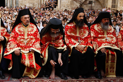 Orthodoxe Geistliche - einer zieht sich den Schuh für die Fußwaschung aus