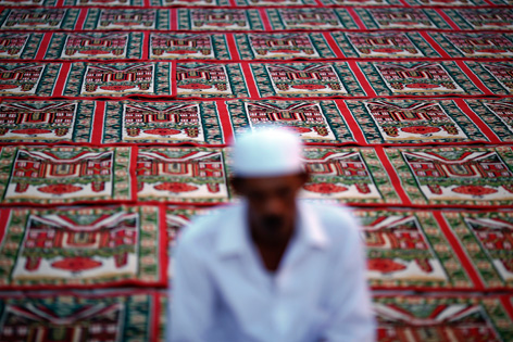 Verschwommene Silhouette eines betenden Muslims auf einem prunkvollen Teppichboden