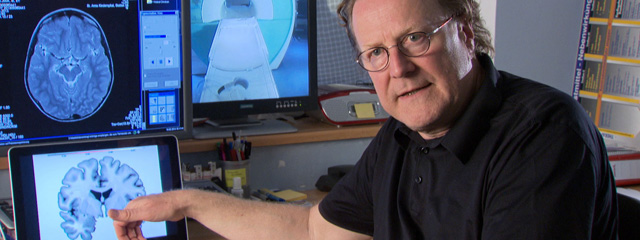 Hirnforscher Joachim Bauer vor Monitoren mit Hirn-Aufnahmen
