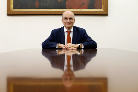 Der Präsident der Vatikan-Bank, Ernst von Freyberg, sitzt an einem mächtigen Holztisch