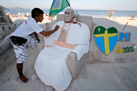 Ein Künstler arbeitet an seiner Sandskulptur von Papst Franziskus am Strand von Copacabana