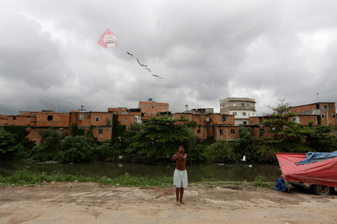 Ein Kind spielt vor einer Reihe brüchiger Häuser mit einem Flugdrachen