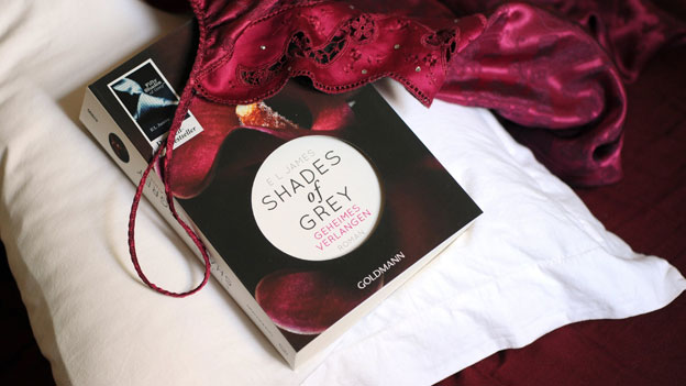 Das Erotikbuch "Shades Of Grey - geheimes Verlangen" liegt mit einem Negligee auf einem Kopfkissen