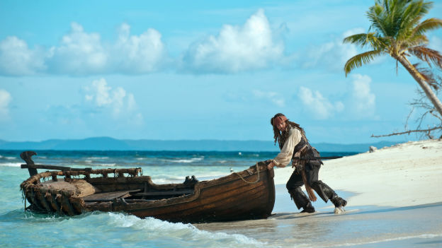 Johnny Depp schiebt ein Boot von einer Insel ins Meer