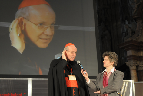 Apostelgeschichte 2010: Kardinal Christoph Schönborn will auf die Katholikinnen und Katholiken in Wien hören. Er steht im Stephansdom vor einem Mikrophon und hält die Hand an sein Ohr.