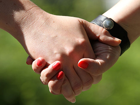 Zwei Frauen halten sich an den Händen