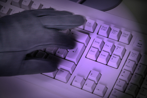 Ein Hand mit Lederhandschuh tippt in eine Tastatur