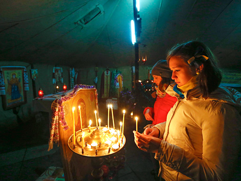 Demonstrantin zündet Kerze in der Zeltkirche in Kiew an