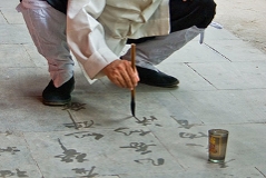 Mönch praktiziert Wasserkalligraphie auf Pflastersteinen