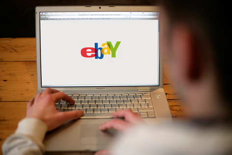 Ein Mann vor einem Laptop, auf dem ein Browserfenster mit eBay geöffnet ist