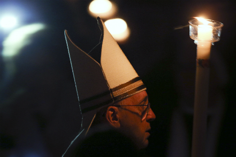 Papst Franziskus mit Kerze im Dunkeln