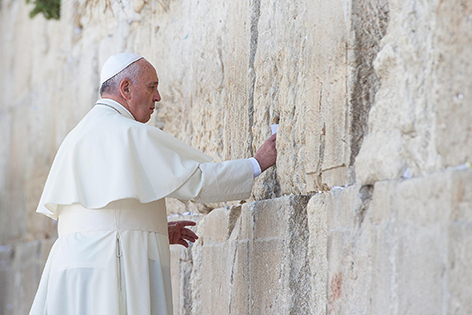 Papst Franziskus steckt einen Zettel in die Klagemauer