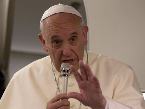 Papst Franziskus mit Mikrofon im Flugzeug