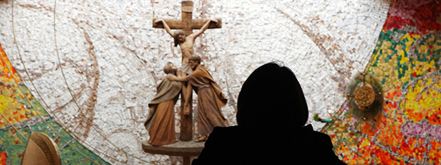 Eine Frau sitzt vor einem Kreuz