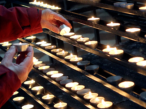 Frau zündet Kerzen in einer katholischen Kirche an