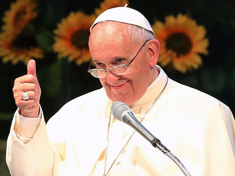 Papst Franziskus vor einem Mikrofon mit Daumen-hoch-Geste