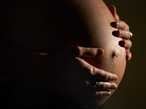 Eine Hochschwangere greift sich an den Bauch