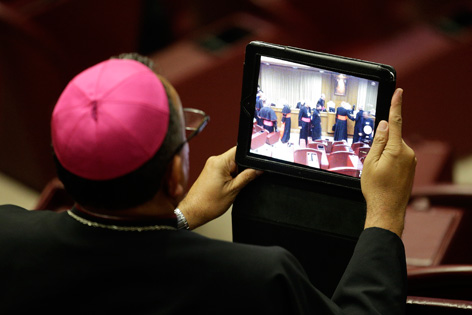 Kardinal schaut in einen Tablet-Computer