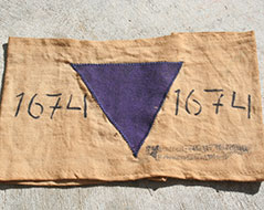 Eine Armbinde aus einem Konzentrationslager mit  einer Nummer und einem violetten Dreieck - zur Kennzeichnung von Zeugen Jehovas.
