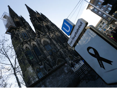Der Kölner Dom und ein Plakat, das mit einer schwarzen Trauerschleife verhängt ist