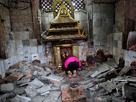 Eine Frau betet in einem zerstörten Indra-Tempel