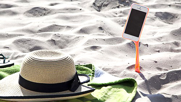 Strohhut im Sand mit Handy