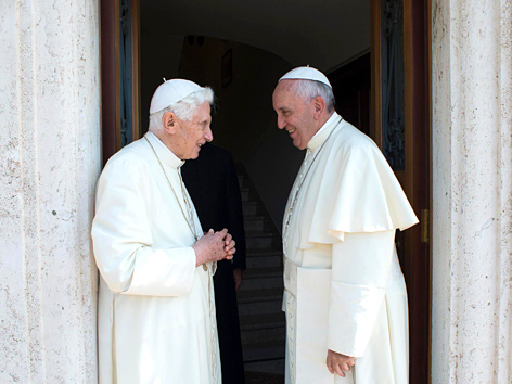 Papst Benedikt XVI. und Papst Franziskus in einem steinernen Türrahmen