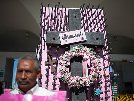 Ein schwarzes Kreuz vor rosa Hintergrund. Für die in Mexiko verschleppten udn ermordeten Frauen
