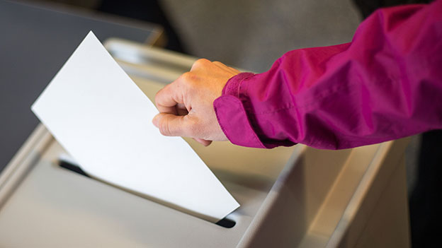 Ein Wähler wirft sein Kuvert in die Wahlurne.