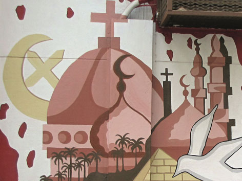 Ein Gemälde auf einer Hauswand mit den religiösen Symbolen Taube, Kreuz, Halbmond