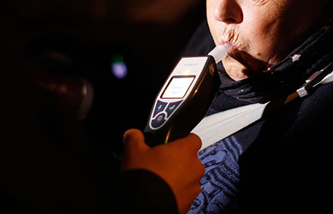Polizist überprüft den Alkoholpegel einer Autofahrerin mit einem  Alkomat