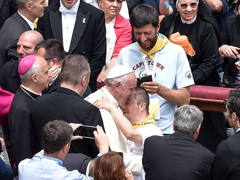 Papst Franziskus umarmt in der Menge auf dem Petersplatz einen Mann mit Down-Syndrom