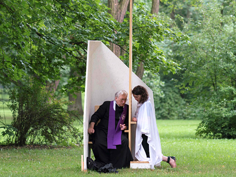 Ein Priester nimmt einer Frau auf einer Wiese im Krakauer Blonia-Park zu Beginn des Weltjugendtags die Beichte ab