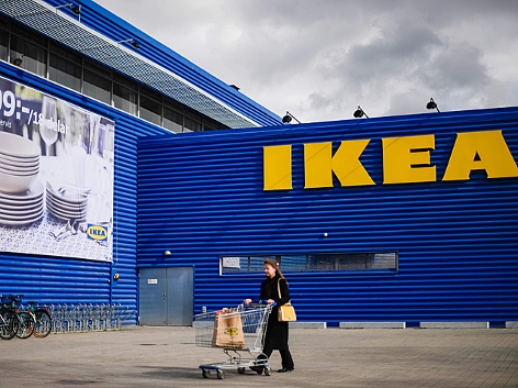Ein Kunde schiebt seinen Einkaufswagen, im Hintergrund eine Ikea-Filiale