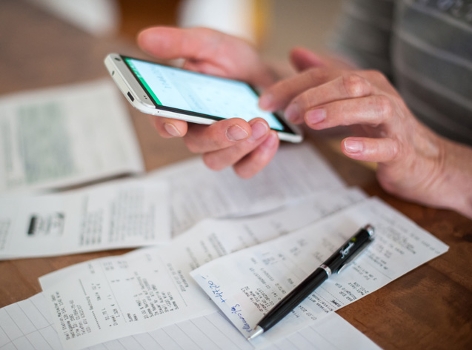 Rechnungen und Hand mit Mobiltelefon