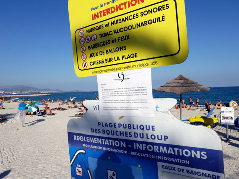 Schild mit Baderegeln an einem französischen Strand. Darunter ein Burkiniverbot.