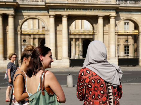 Eine Frau mit Kopftuch und zwei ohne vor dem Conseil d'Etat (Gericht) in Paris