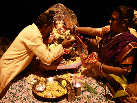 Gläubige verehren eine Statue des Gottes Ganesha