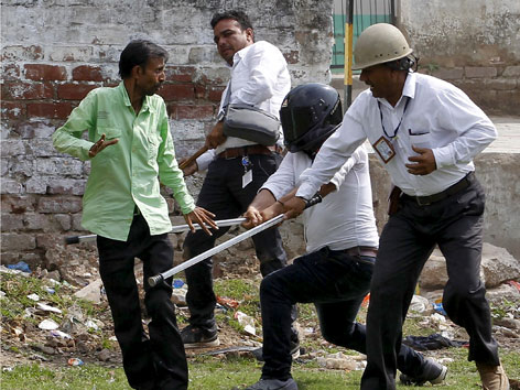 Polizisten gehen mit Stöcken auf einen Dalit los