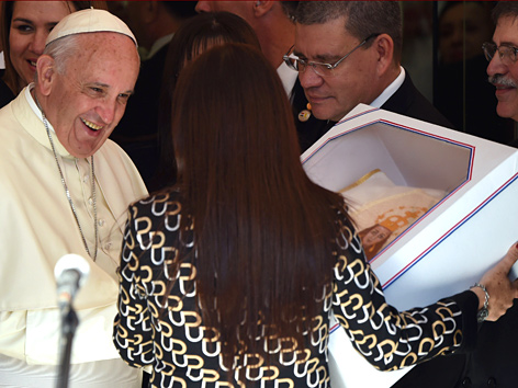 Eine Frau überreicht Papst Franziskus ein Geschenk bei einem Besuch eines Kinderspitals in Asuncion, Paraguay