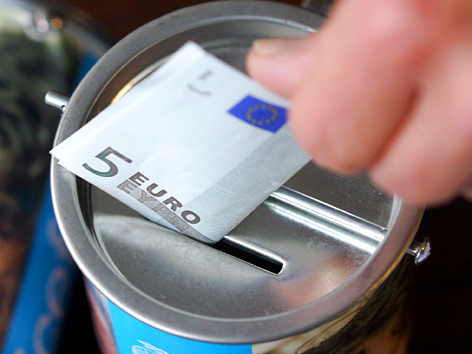 Ein Fünf-Euro-Schein wird in eine Sammelbox gesteckt
