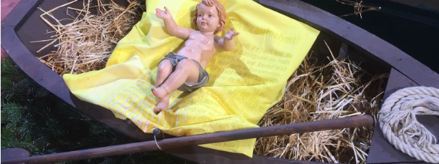 Figur des Christuskindes mit ausgebreiteten Armen in einem Fischerboot